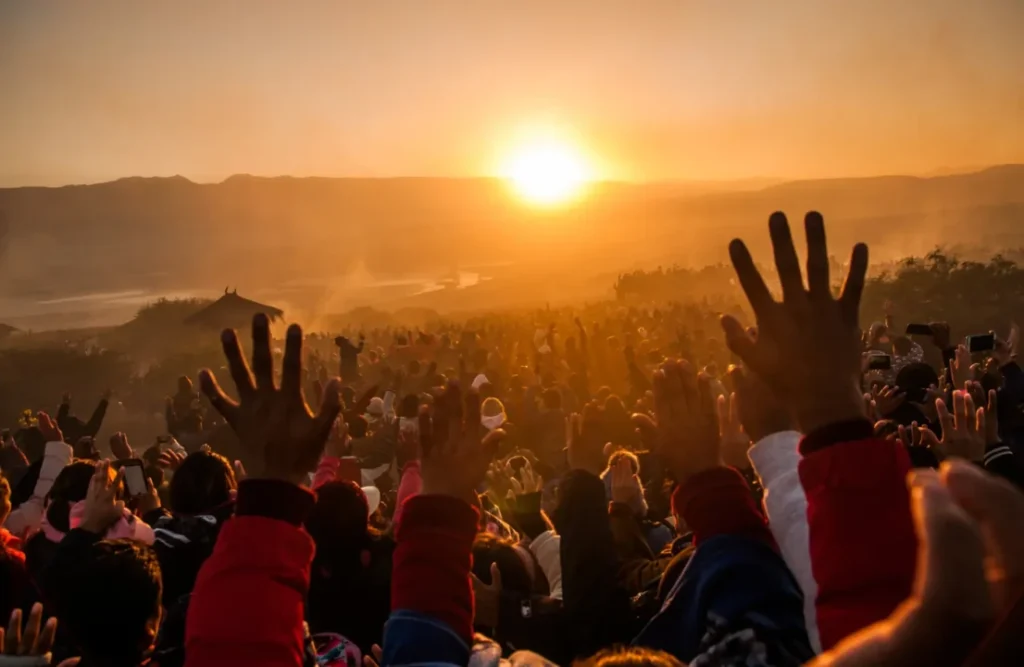 A crowd partying and raising their hands as the sun sets.